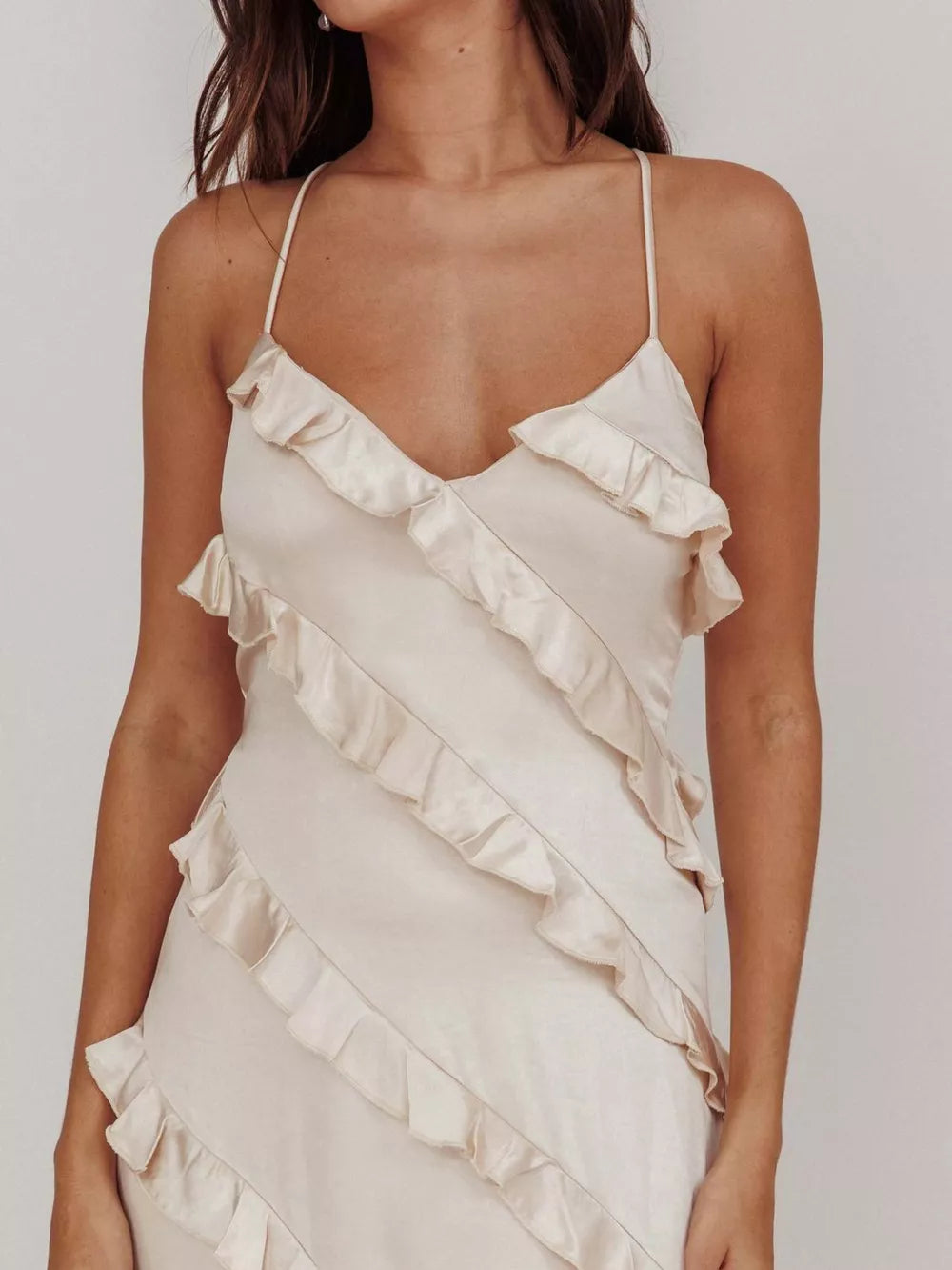Beige ruffled spaghetti strap maxi dress with diagonal ruffle detailing.