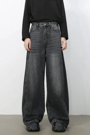 Dark wash denim trousers with exaggerated wide legs and a relaxed fit.