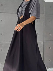 Black pleated overall dress with pockets, shown with a grey t-shirt.