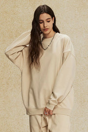 Oversized tan crewneck sweatshirt with subtle shoulders and crew neckline.