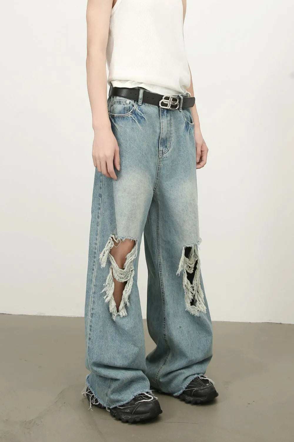 Distressed wide-leg denim jeans in medium wash with fraying and ripped details.
