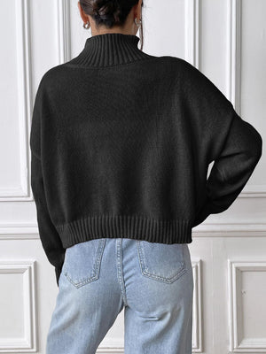 Black knit turtleneck sweater with ribbed trim, styled with light wash jeans.