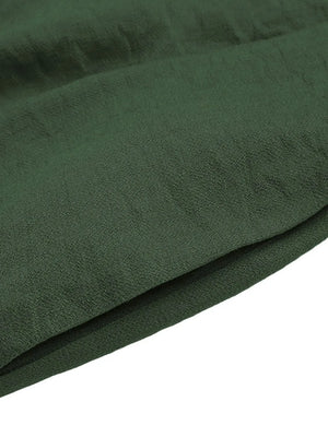 Dark green pleated shorts detail showing fabric texture and folded hem.