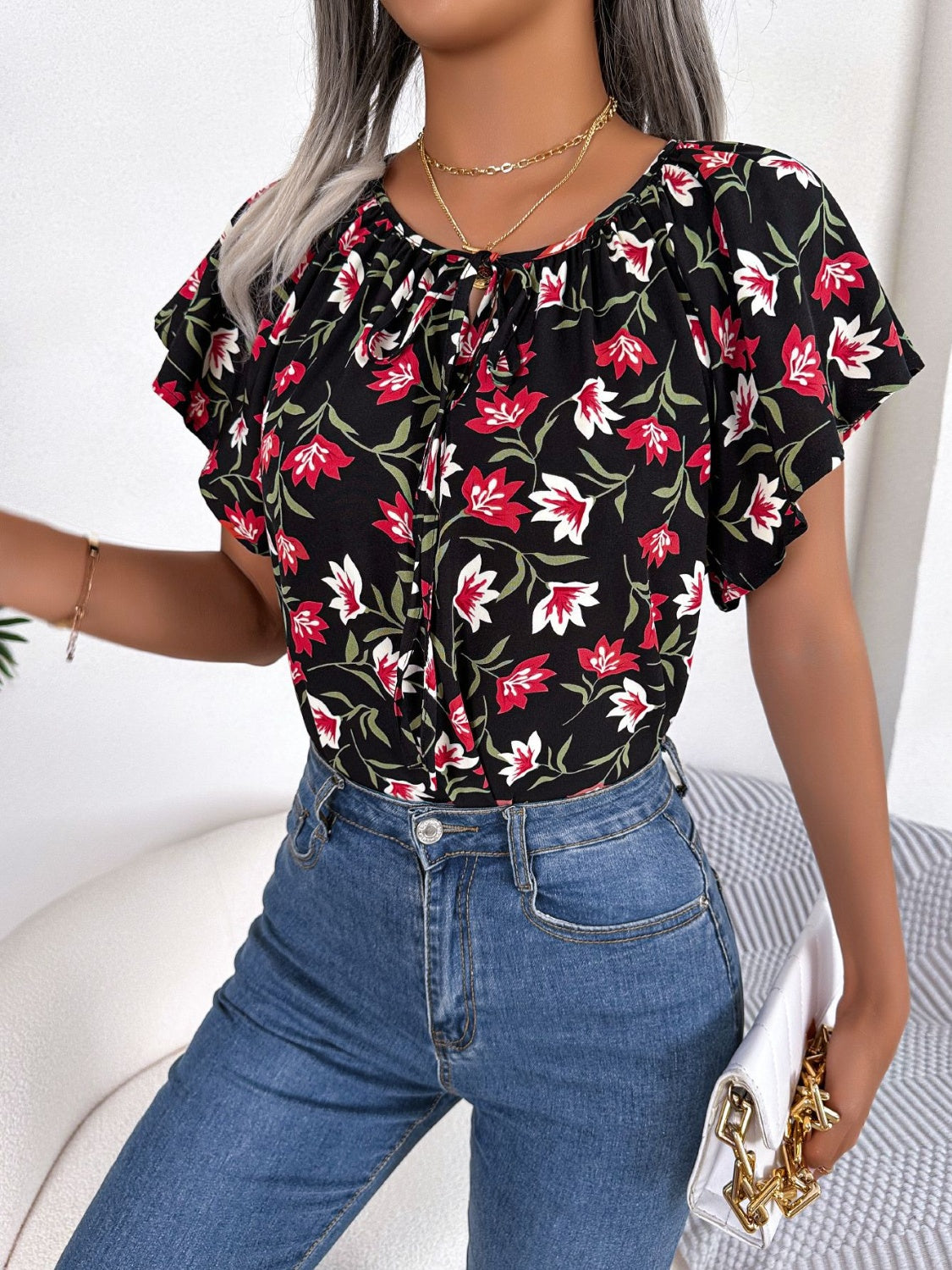 Floral ruffle sleeve tie-neck blouse in black with red and white flowers.