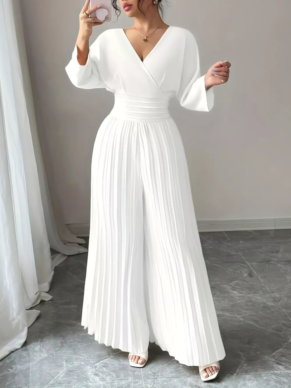 Elegant white pleated wide-leg jumpsuit with a cinched waist and V-neckline.