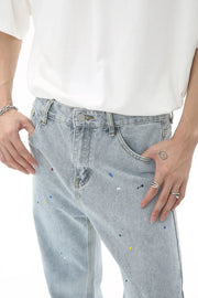 Light wash denim trousers with colorful paint splatters and a slouchy fit.
