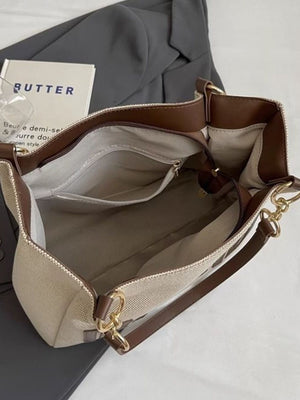 Textured canvas shoulder bag with brown trim and gold chain accents, open interior view.