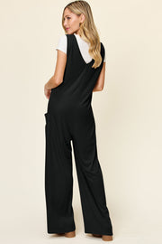 Black wide-leg pocket jumpsuit with deep V-neck and side pockets, styled with a white t-shirt.