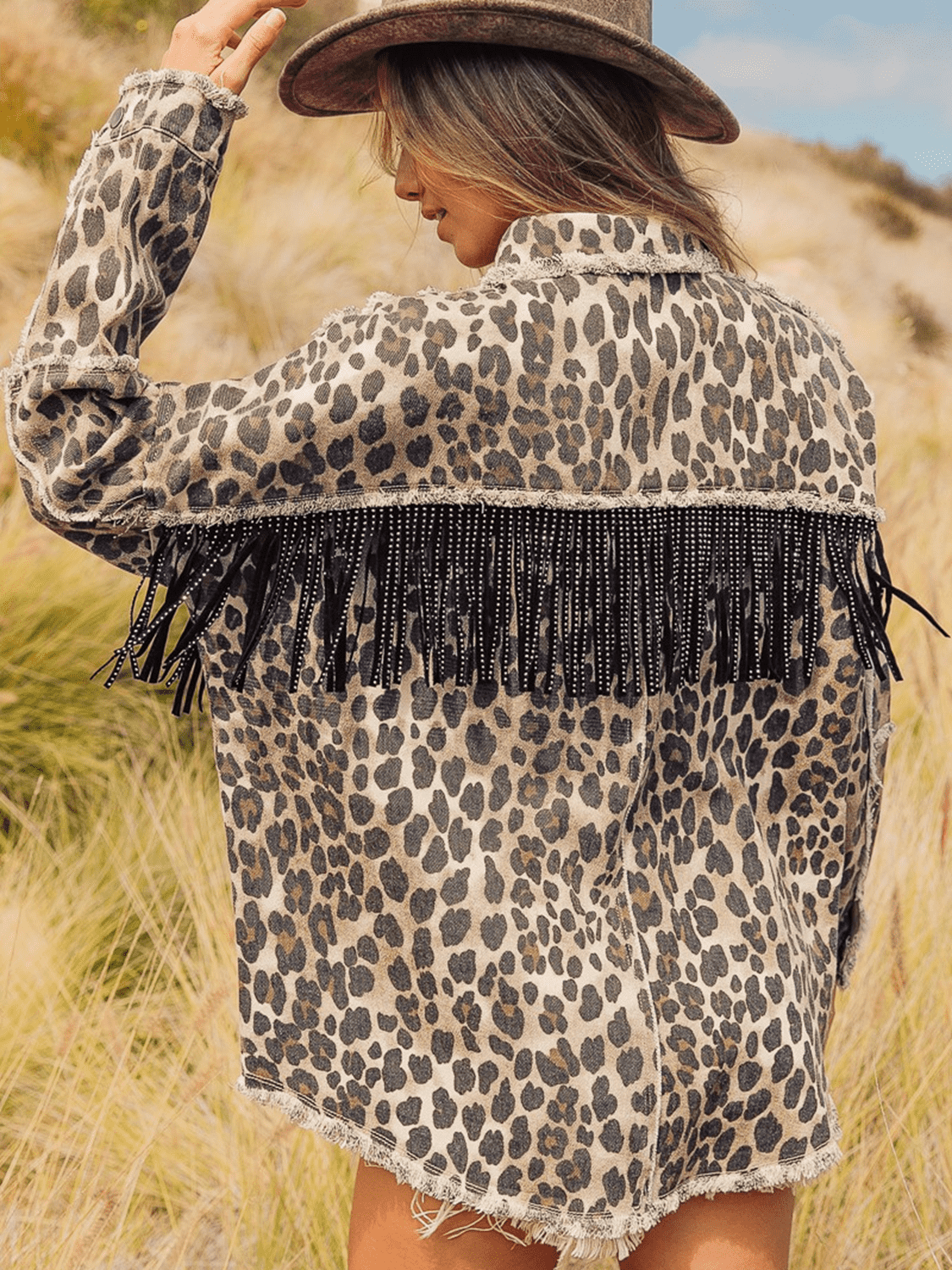 Leopard print denim jacket with collared neck and black fringe embellishment.