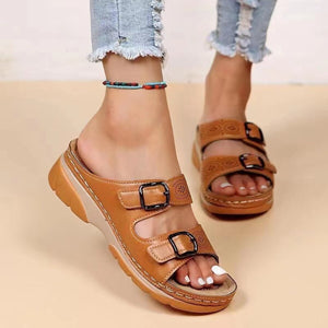 Chic double buckle open-toe sandals in tan with decorative cutouts and black buckles.
