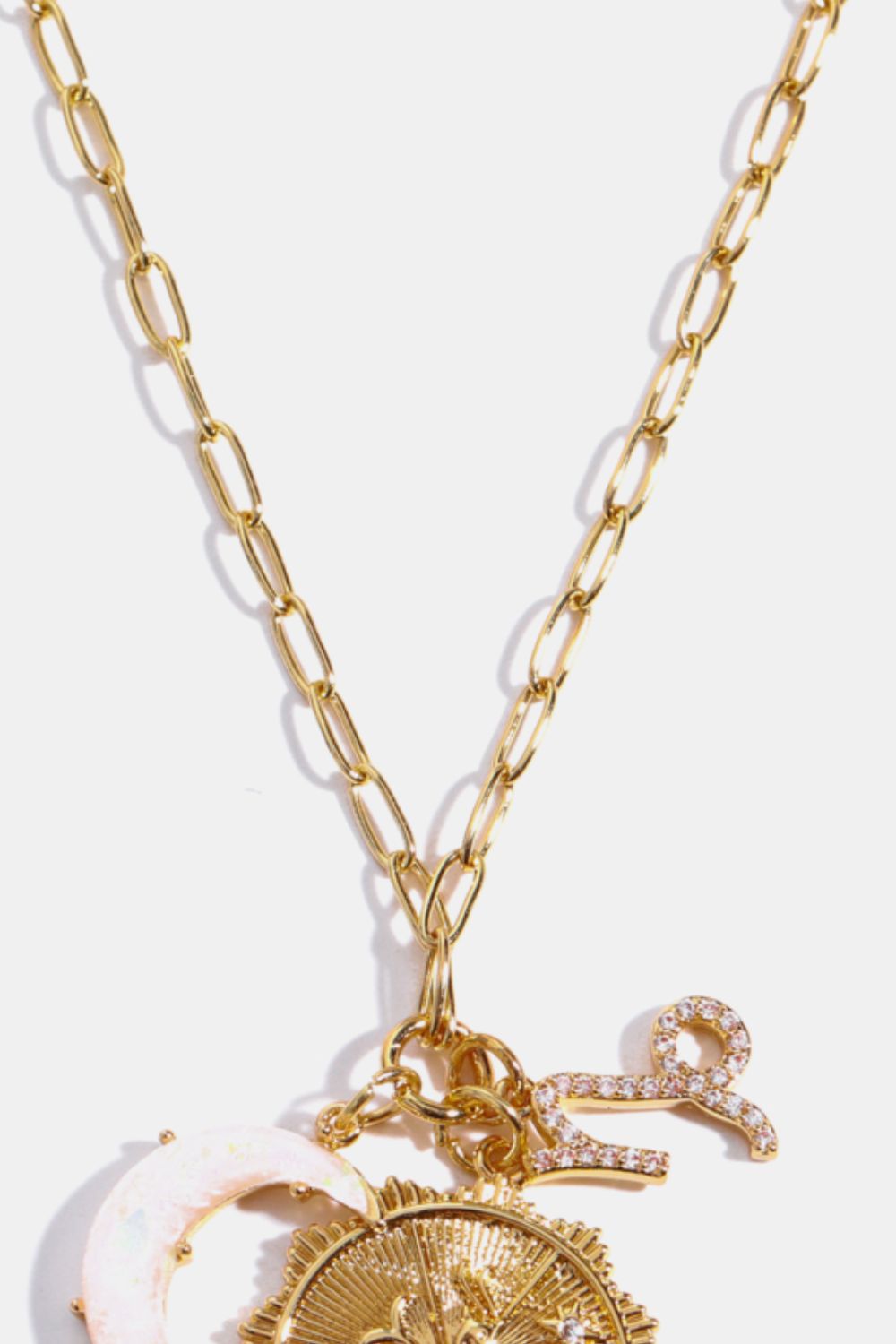Gold chain pendant necklace with celestial charms including a moon and zodiac symbol.