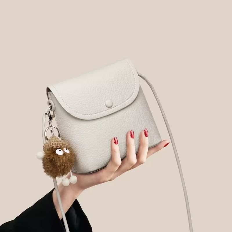 White pebbled pu leather crossbody bag with button closure and cute keychain