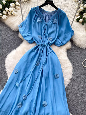 Blue floral maxi dress with puff sleeves, V-neck, tie waist and button front.