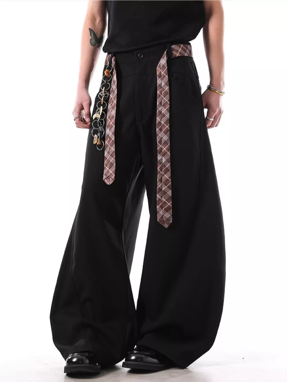 Black wide-leg sweatpants with plaid strap detail and chain accessory.