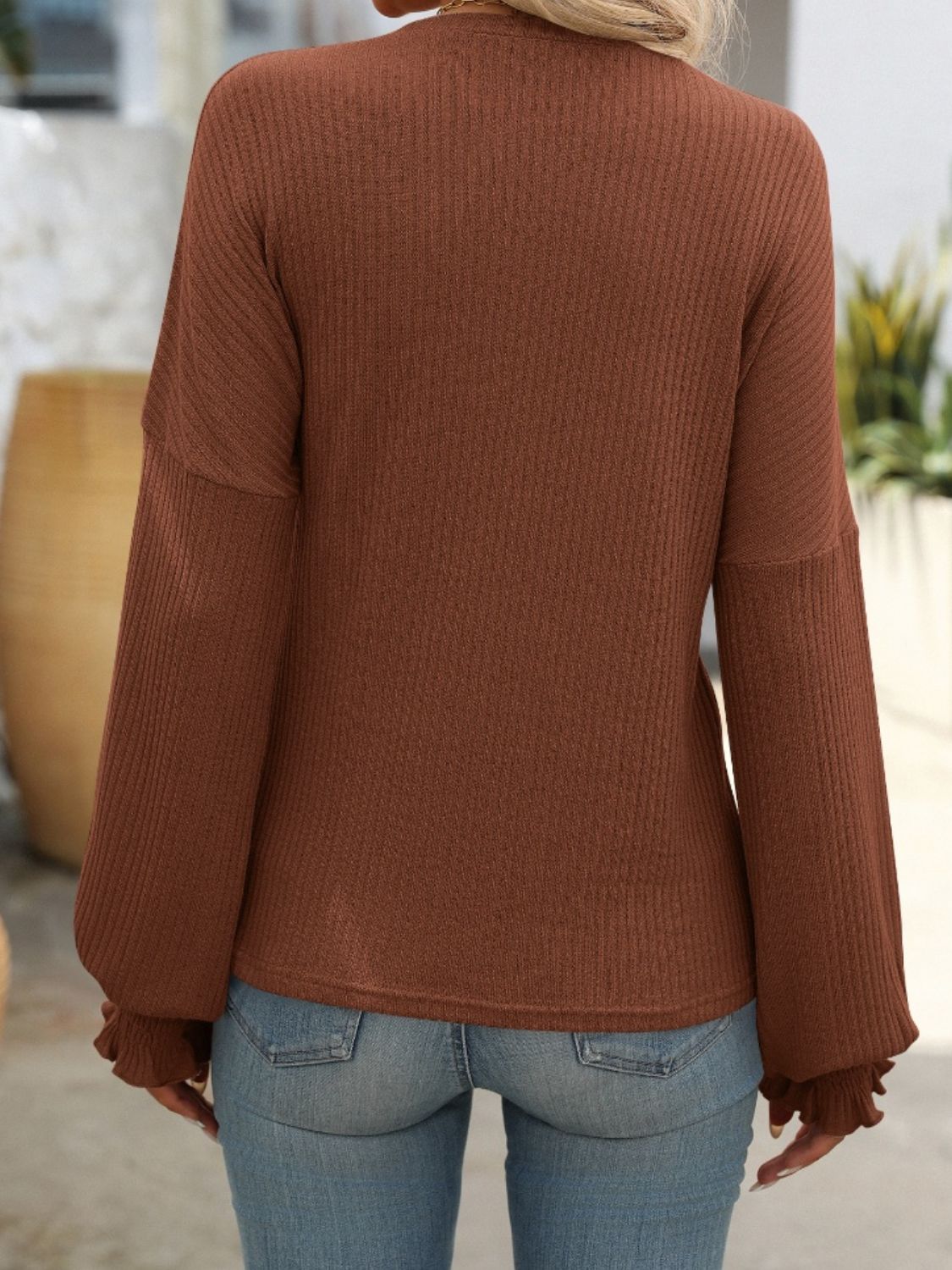 Textured ribbed knit blouse in dark brown with ruffled cuffs and long sleeves.