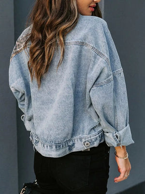 Distressed denim trucker jacket with leopard print detail on shoulders, buttoned front, and cuffed sleeves.