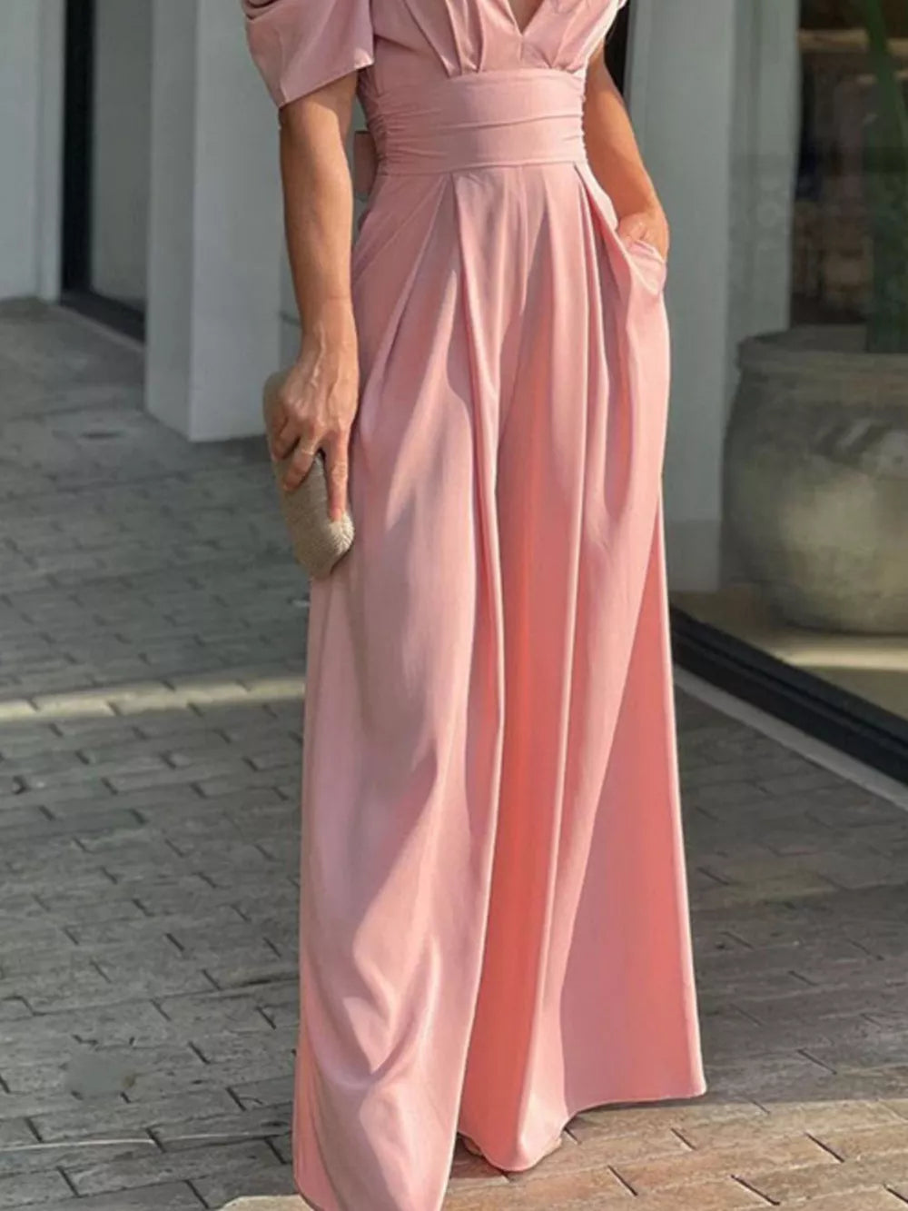 Watermelon pink romper with cinched waist, deep V-neck, and puff sleeves.