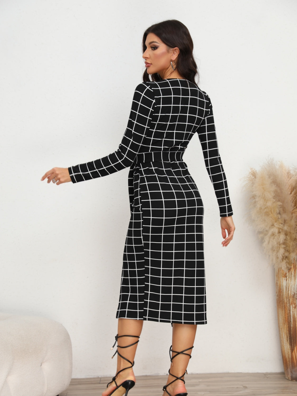 Black and white grid wrap midi dress with long sleeves and belted waist.
