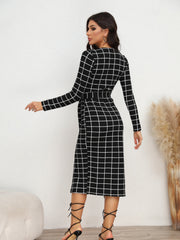 Black and white grid wrap midi dress with long sleeves and belted waist.