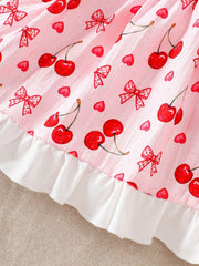 Baby dress with cherry and bow print on pink cotton, featuring a white ruffle hem.