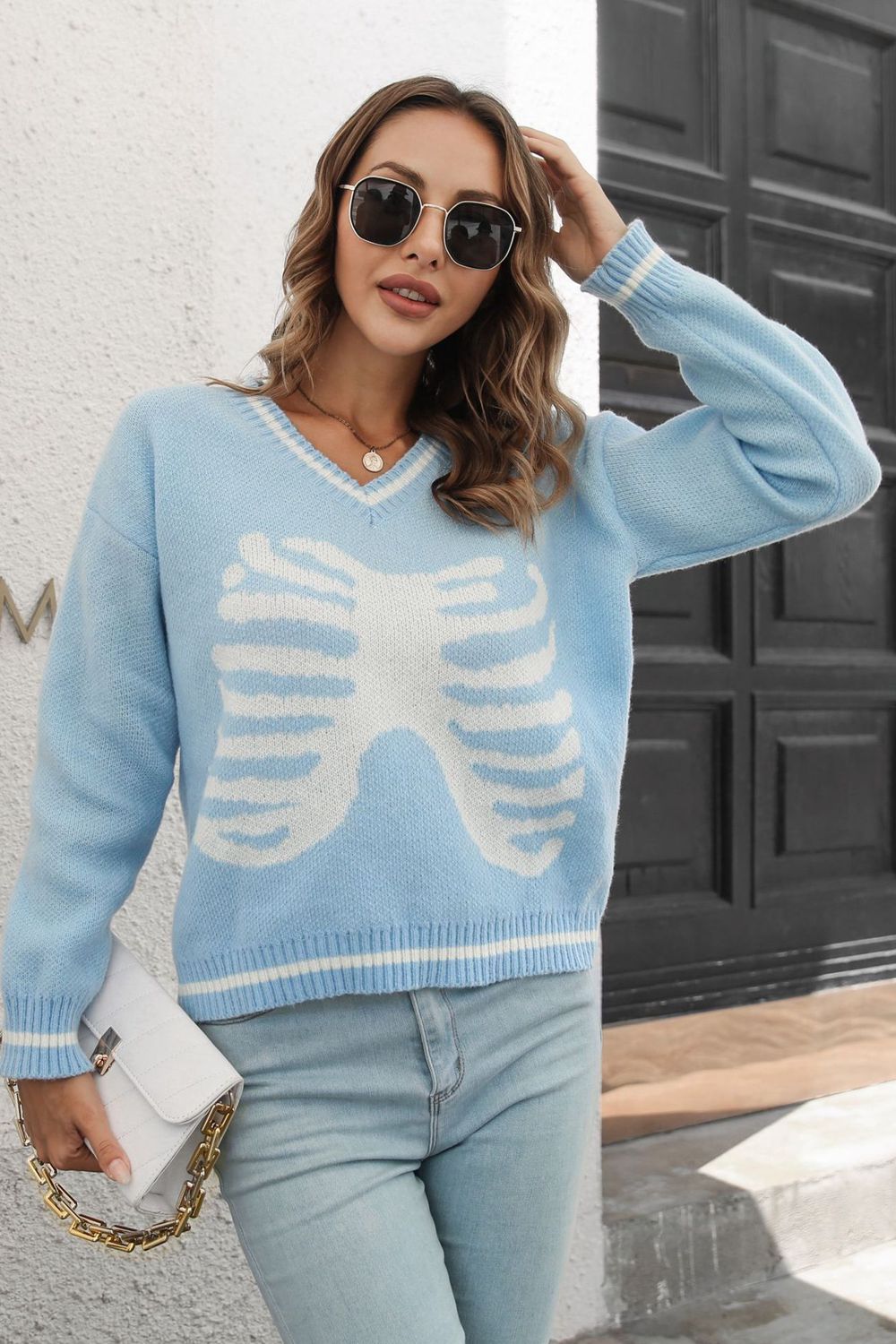 Light blue acrylic v-neck sweater with white ribcage graphic and striped cuffs.