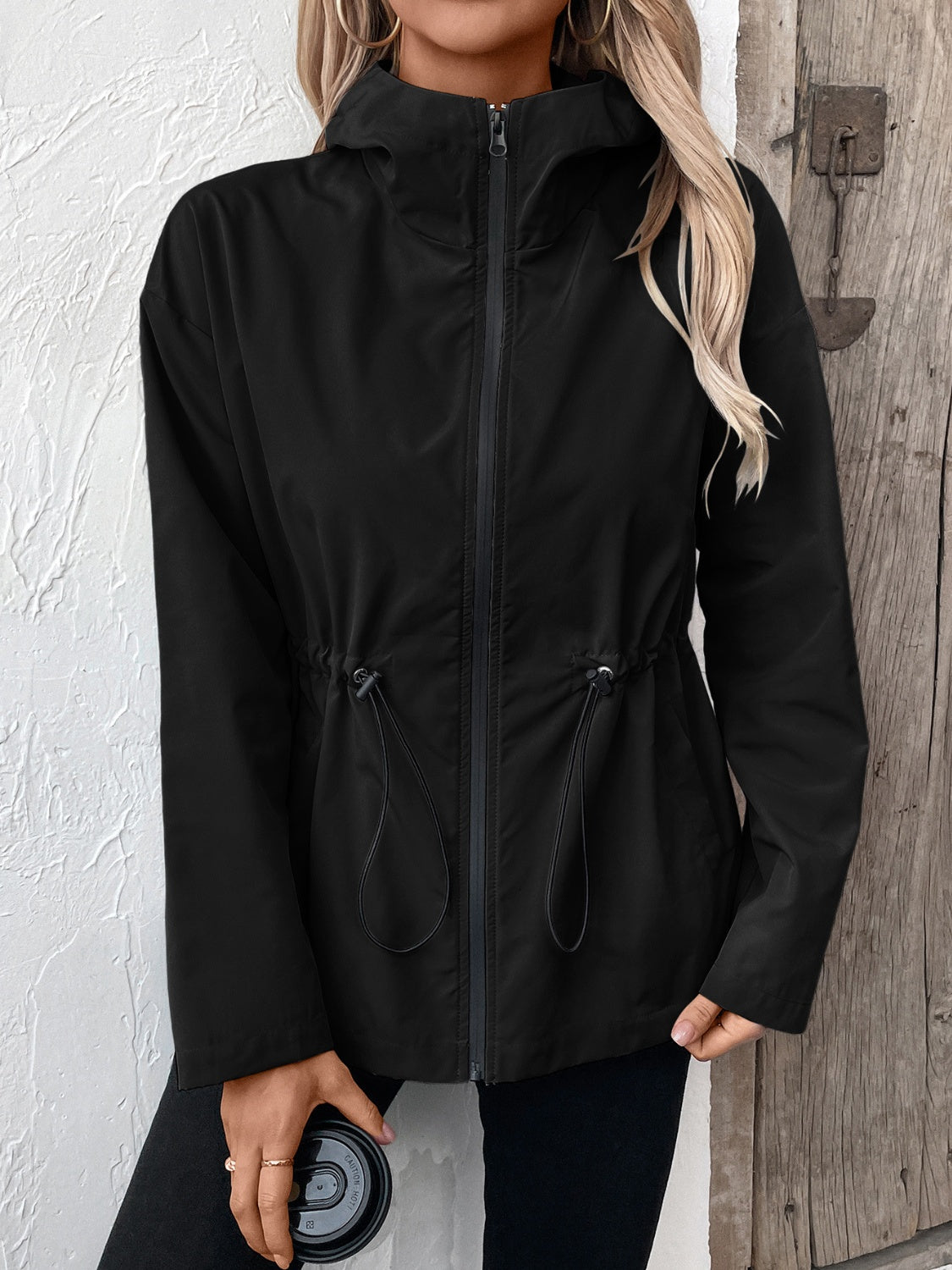 Black utility jacket with cinched waist, drawstring details, and hood.