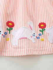 Embroidered bunny and flower detail on a pink and white striped cotton baby dress.