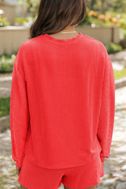 Orange-red ribbed lounge set with crew neck long sleeve top and shorts.