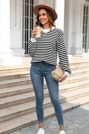 Black and white striped knit crewneck sweater with crew neckline and long sleeves.