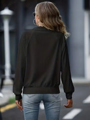 Black ribbed zip-up track jacket with raglan sleeves and elastic cuffs.