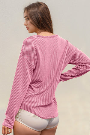 Pink ribbed long sleeve top with crew neck and relaxed fit.