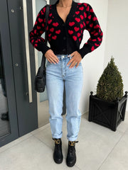 Black acrylic knit cardigan with red heart pattern, puff sleeves, and V-neck.