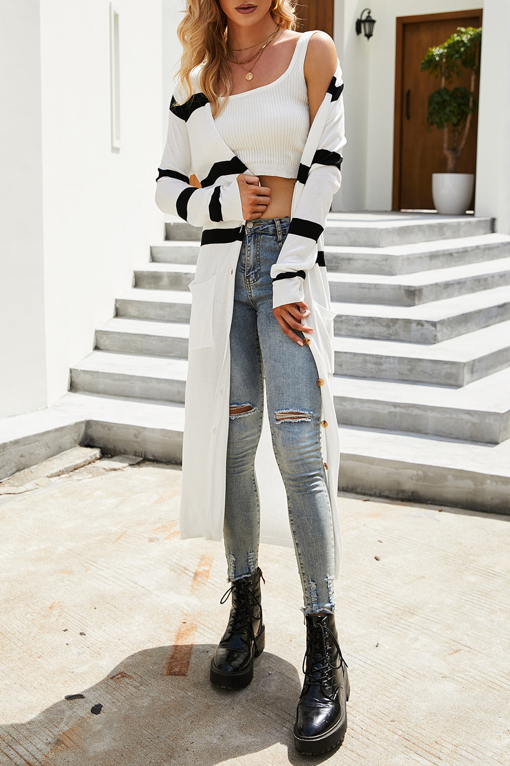 Longline white cardigan with black stripes, button front, and pockets.