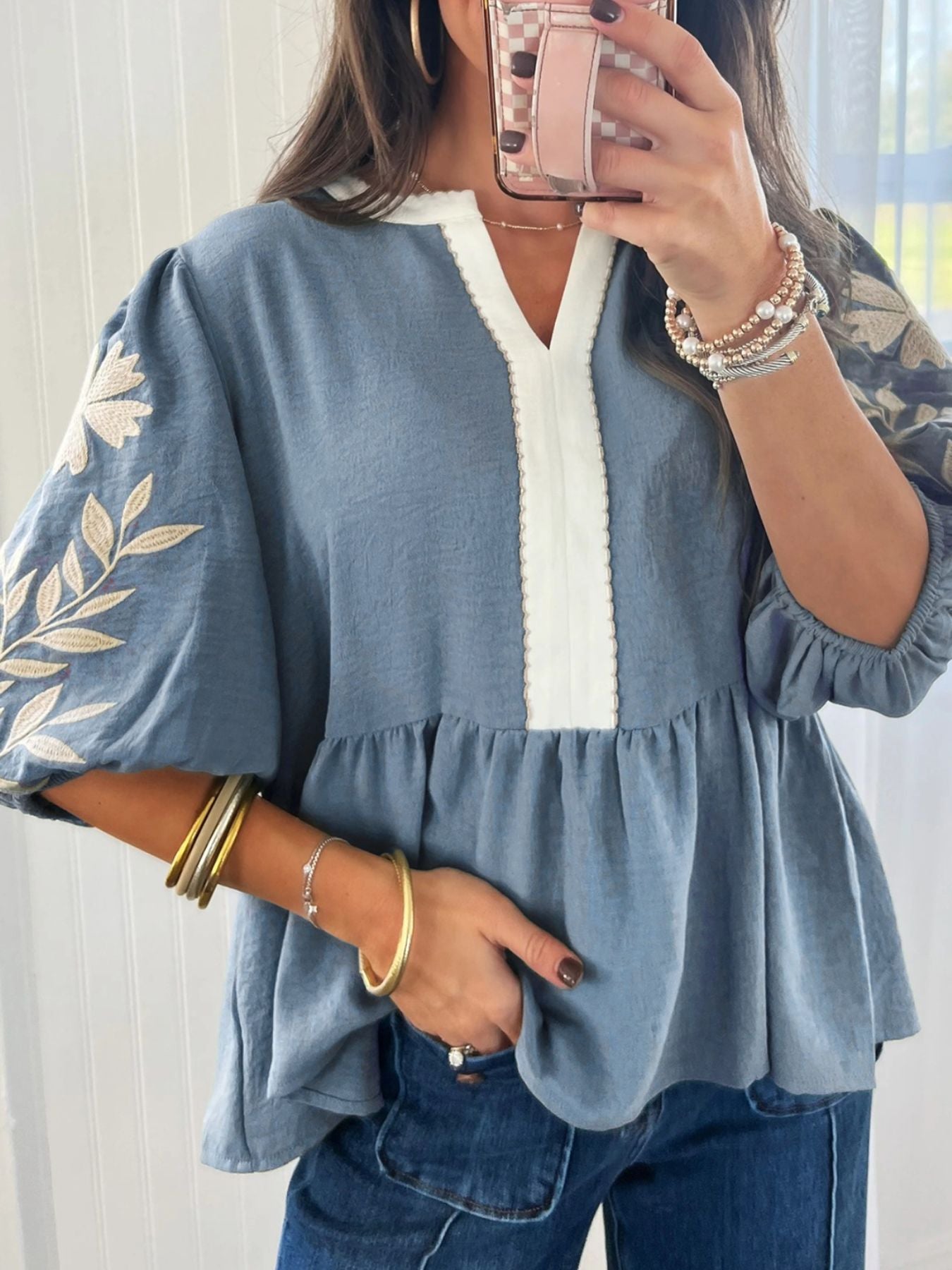 Blue embroidered peplum blouse with elbow sleeves, white contrast neckline, and ruffled hem.