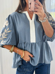 Blue embroidered peplum blouse with elbow sleeves, white contrast neckline, and ruffled hem.