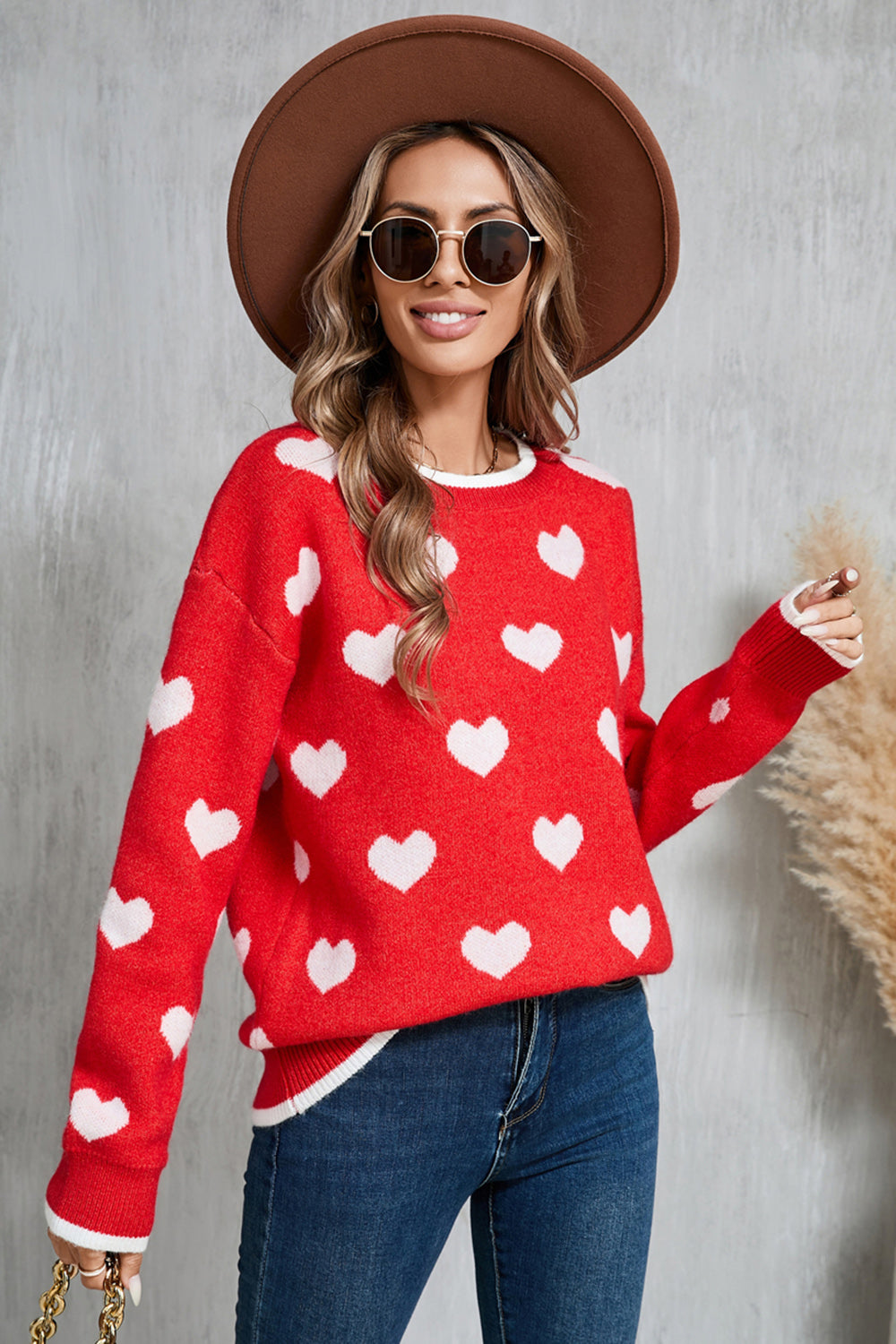 Red acrylic crewneck sweater with white heart intarsia pattern and white trim.