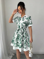White mini dress with green floral print, collared, short sleeves, and tie belt.