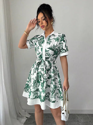 White mini dress with green floral print, collared, short sleeves, and tie belt.