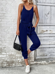 Dark blue chain-strap gathered waist jumpsuit with tie belt and gathered ankles.