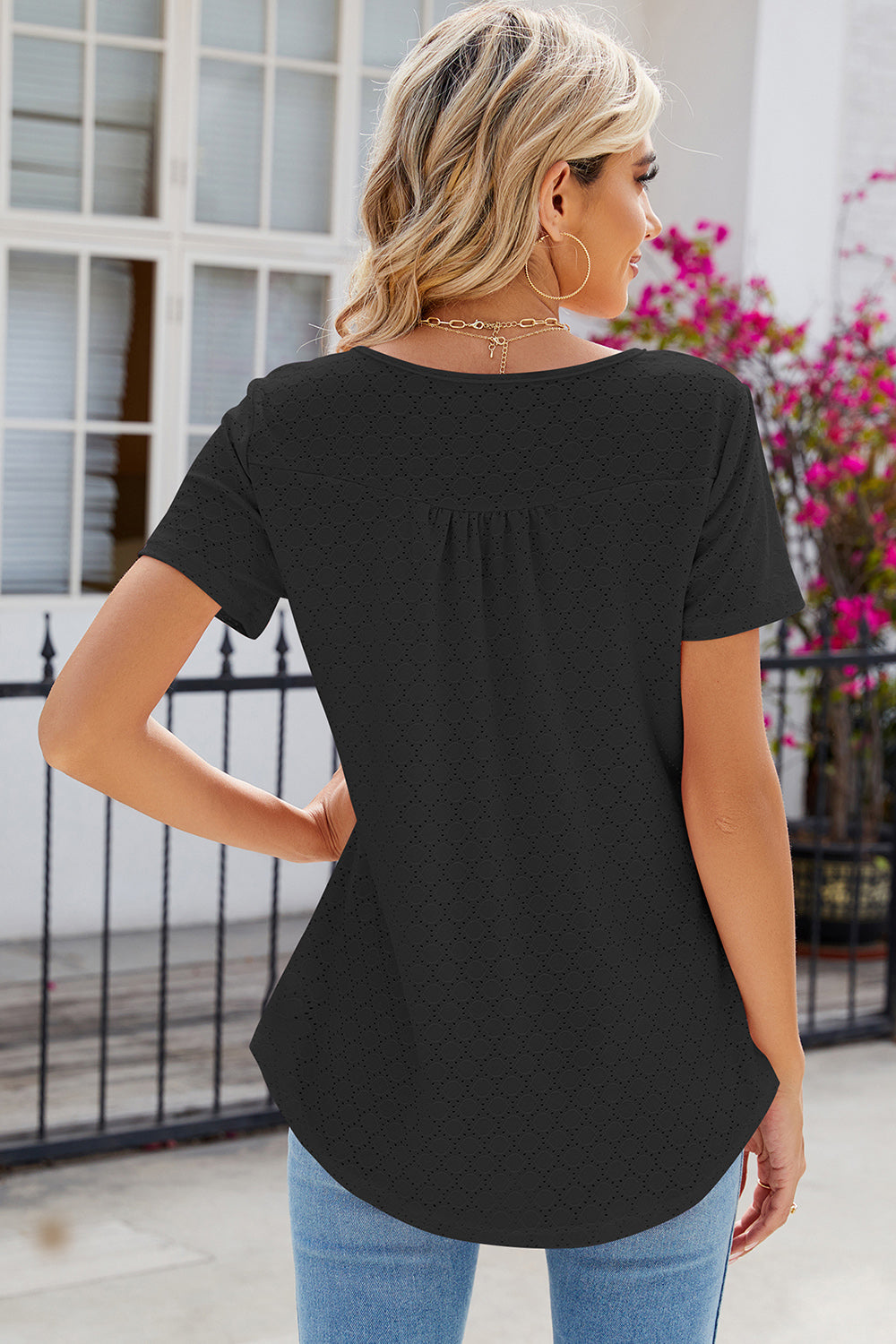 Black eyelet yoke gathered henley shirt with short sleeves and a curved hem.