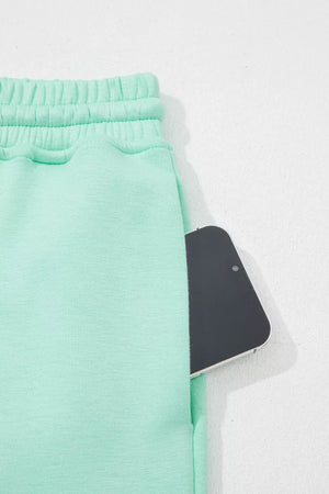 Mint green drawstring lounge pants with a pocket holding a smartphone.