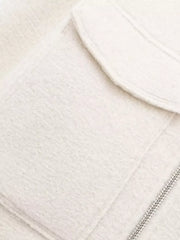 White cropped zip-up jacket with textured fabric and chest pockets.