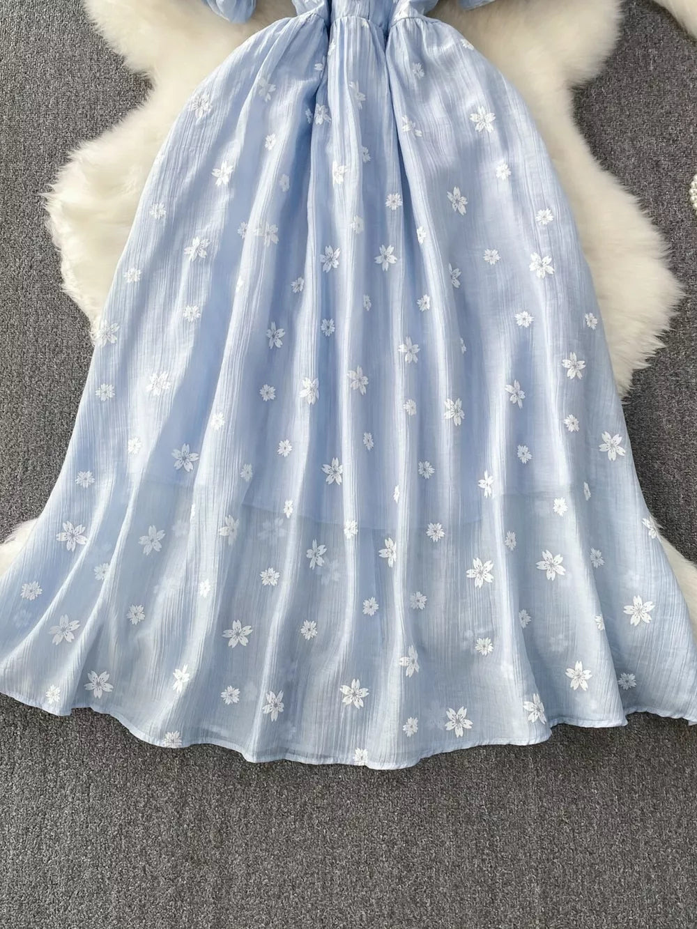 Light blue midi dress with white floral embroidery and puff sleeves.