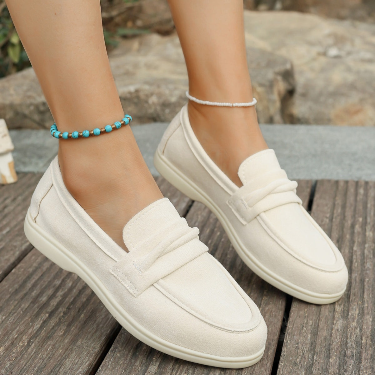 Beige classic round toe slip-on loafers with a decorative strap detail.
