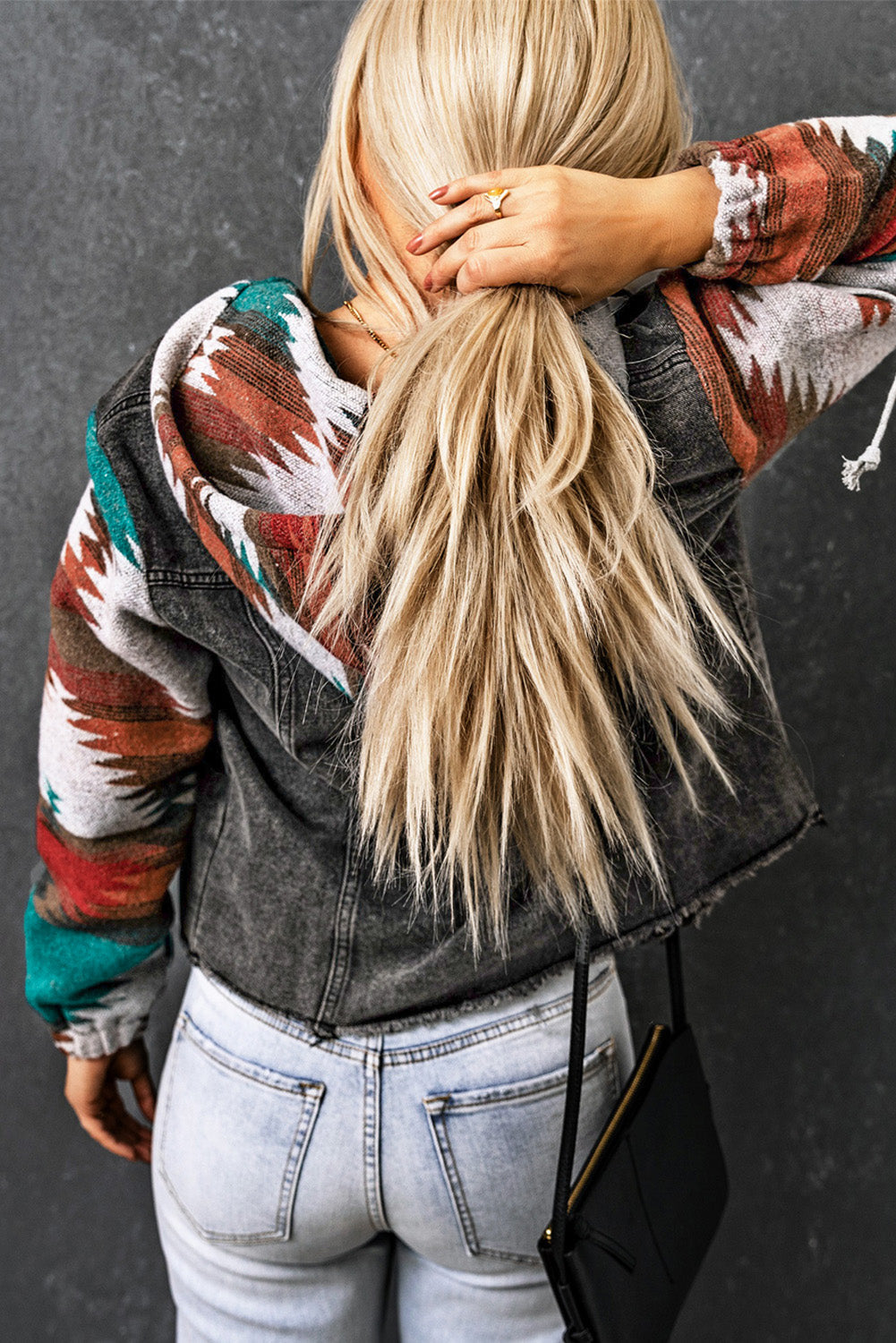 Southwestern print denim hoodie jacket with a dark gray wash and colorful geometric sleeves.