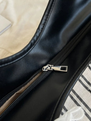Beige shopper bag with black and white stripes and a lace bow detail, showing a close-up of the zipper.