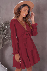 Wine ruffled mini dress with bow-tie waist and long sleeves.