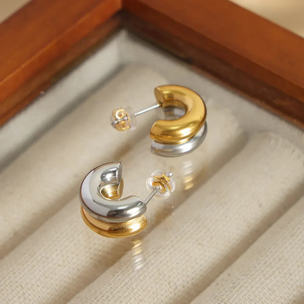 Dual-tone sculptural C-hoop earrings in gold and silver with a polished finish.