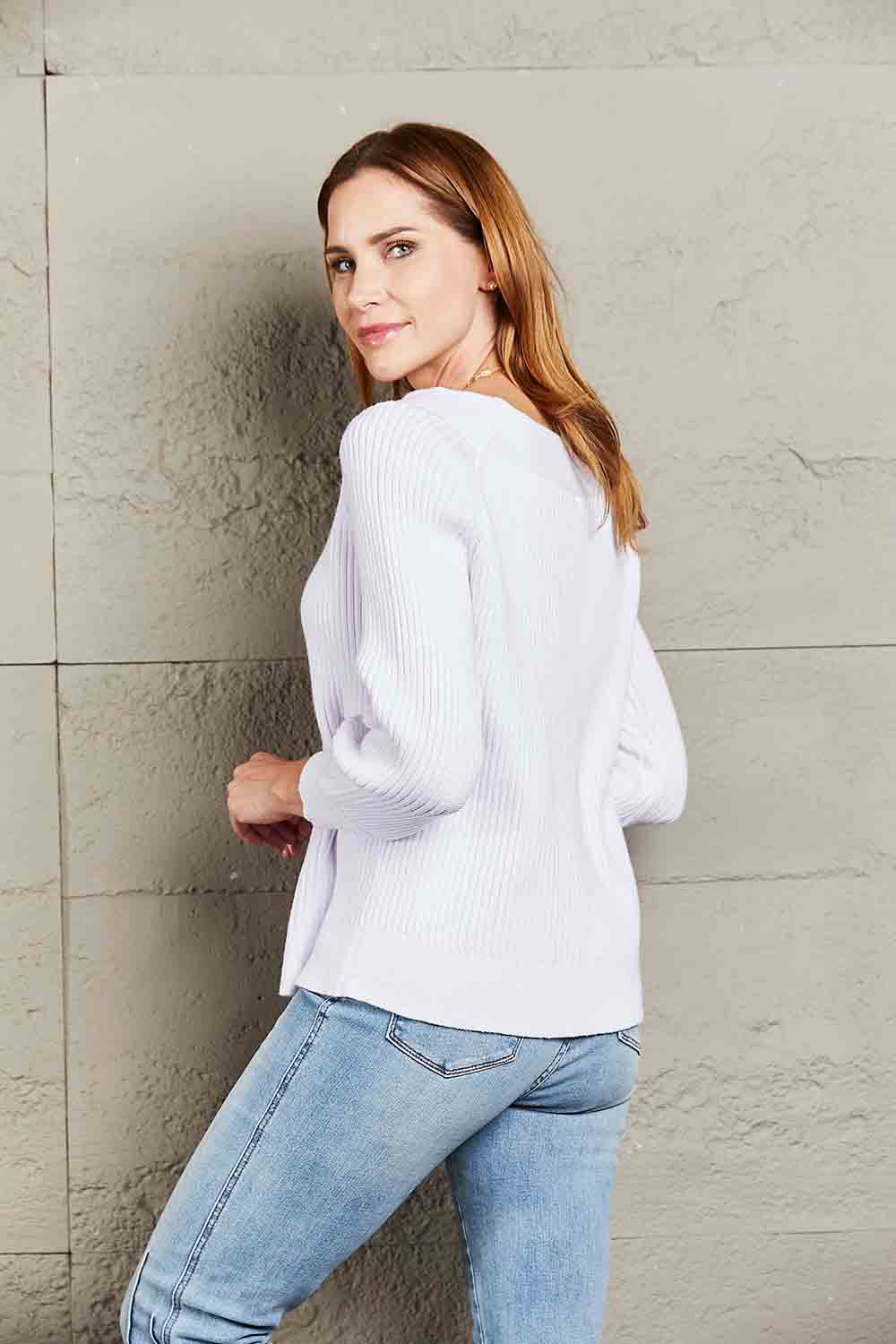 White ribbed knit sweater with boatneck and puff sleeves, styled with jeans.