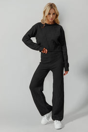 Black textured knit loungewear set with crew neck sweater and wide leg pants.